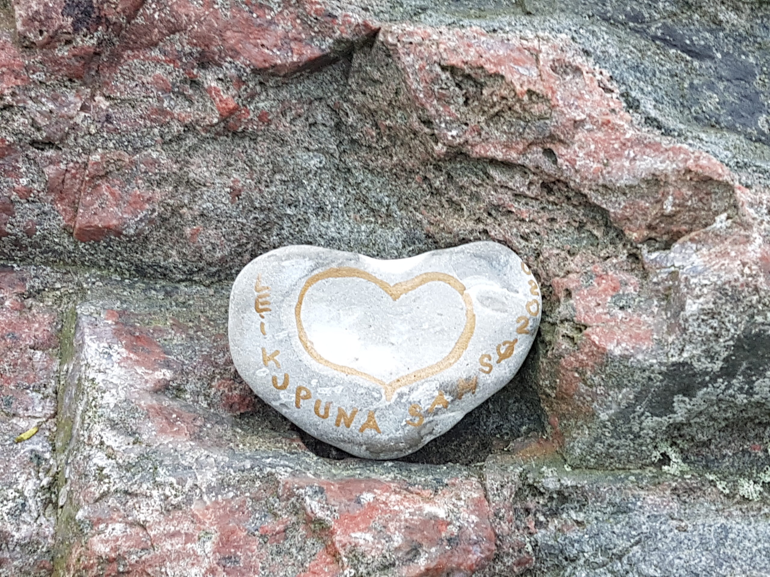Ein herzförmiger Stein an einer Felswand.